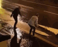 大雨中,一对夫妻在路边开心地玩儿了起来